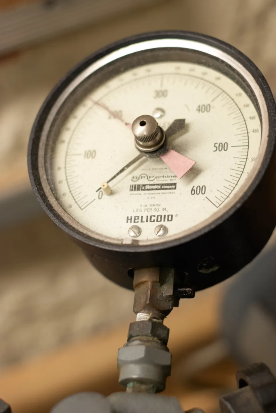 A single analogue pressure gauge on industrial pipework, needle in sharp focus