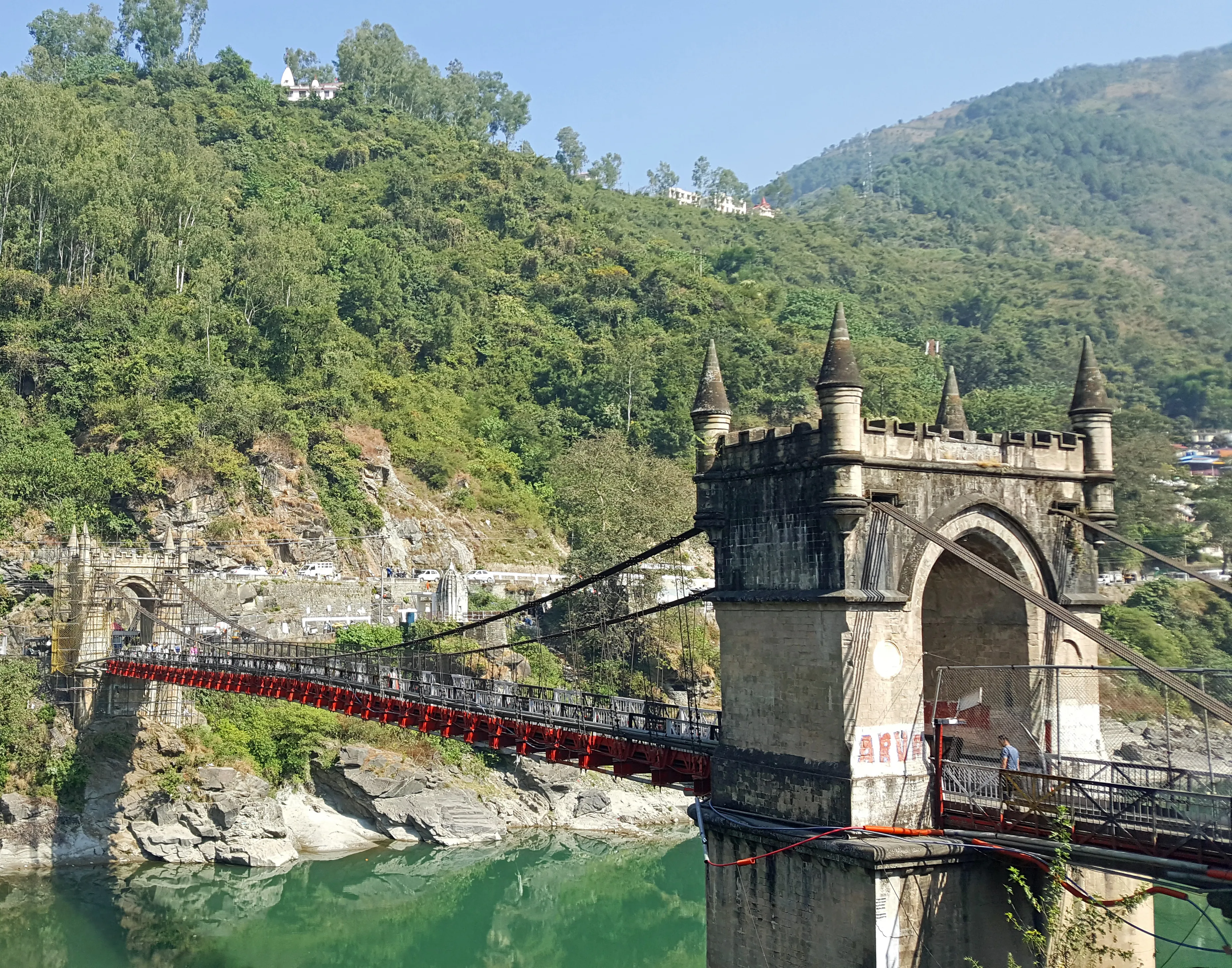 A narrow suspension footbridge held up by a small number of visible cables